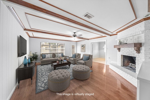 living room with ornamental molding, a brick fireplace, hardwood / wood-style floors, and ceiling fan