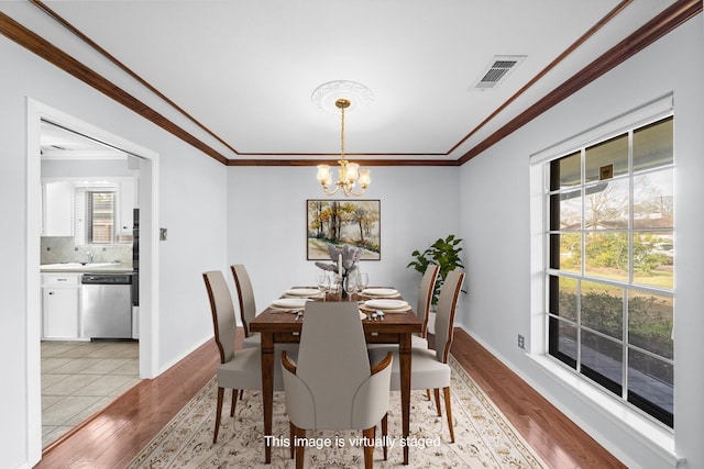 dining room with crown molding, light hardwood / wood-style floors, and a chandelier