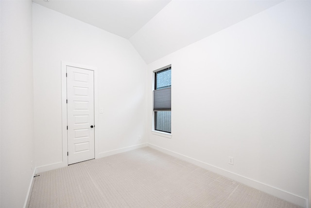 carpeted empty room with lofted ceiling