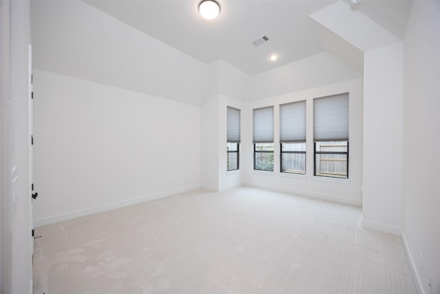 spare room featuring lofted ceiling and light colored carpet