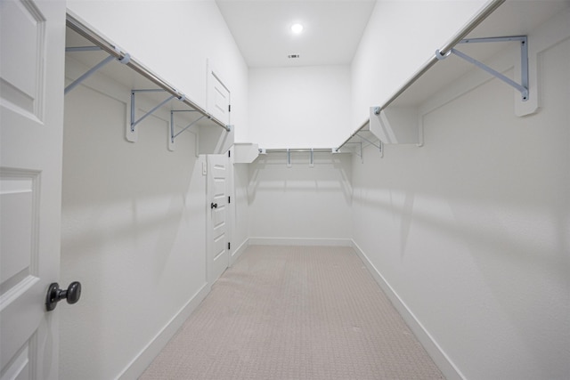 walk in closet with light colored carpet