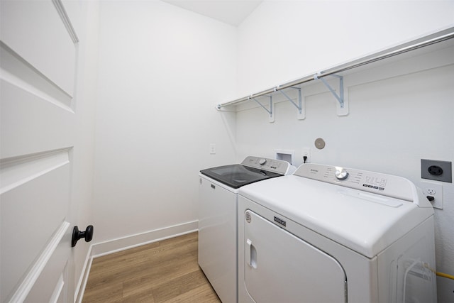 clothes washing area featuring washing machine and clothes dryer and wood-type flooring