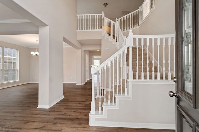 foyer entrance featuring an inviting chandelier, a wealth of natural light, crown molding, and dark hardwood / wood-style floors