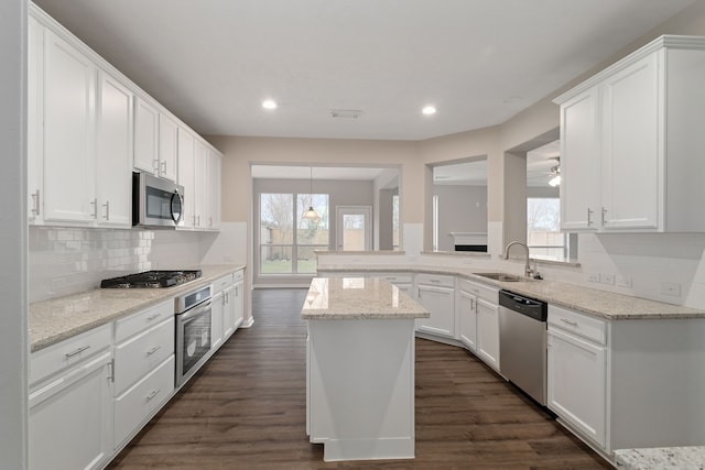 kitchen with light stone counters, dark wood-type flooring, stainless steel appliances, white cabinets, and sink