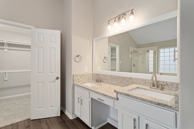 bathroom with vaulted ceiling, a shower with shower door, wood-type flooring, and vanity