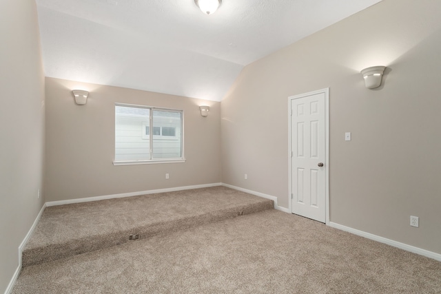 empty room with vaulted ceiling and carpet