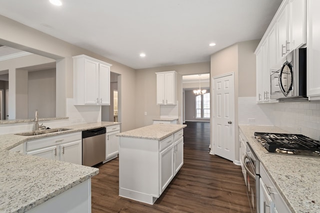 kitchen with stainless steel appliances, a center island, dark hardwood / wood-style flooring, light stone counters, and white cabinets