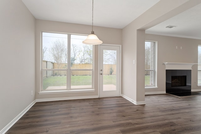 unfurnished dining area with a healthy amount of sunlight, dark hardwood / wood-style floors, and a fireplace