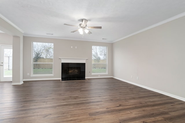 unfurnished living room featuring dark hardwood / wood-style flooring, a tiled fireplace, ceiling fan, and crown molding