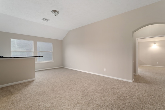 unfurnished living room with light colored carpet and vaulted ceiling