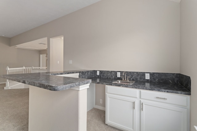 kitchen with sink, white cabinetry, a kitchen breakfast bar, kitchen peninsula, and light colored carpet