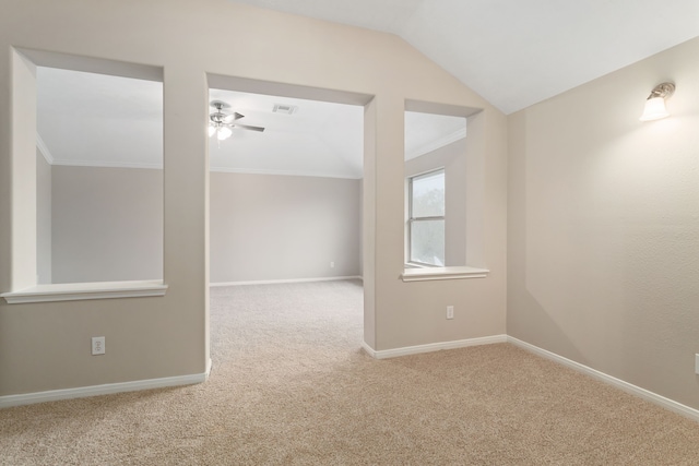 empty room with vaulted ceiling, ceiling fan, crown molding, and carpet flooring