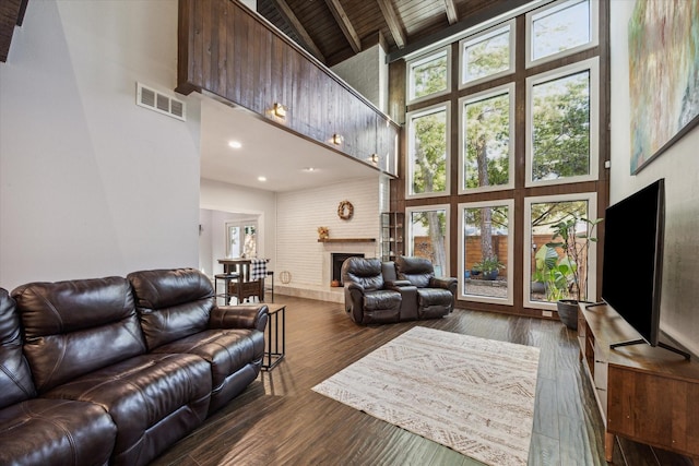 living room with beamed ceiling, high vaulted ceiling, dark hardwood / wood-style floors, plenty of natural light, and a fireplace