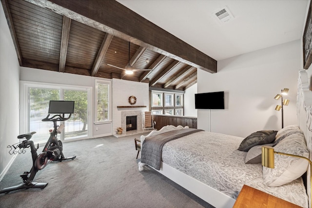 bedroom featuring a brick fireplace, lofted ceiling with beams, wood ceiling, and multiple windows