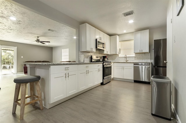 kitchen with light stone countertops, white cabinets, kitchen peninsula, and appliances with stainless steel finishes