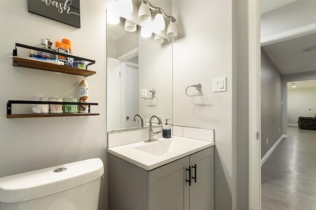 bathroom featuring toilet, vanity, and hardwood / wood-style floors