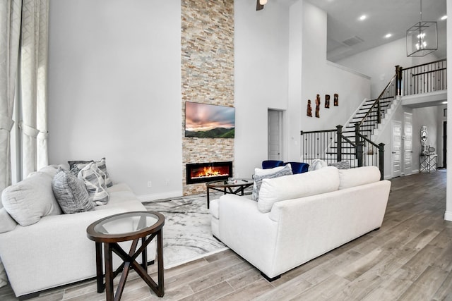 living room featuring a high ceiling, a fireplace, a chandelier, and hardwood / wood-style floors