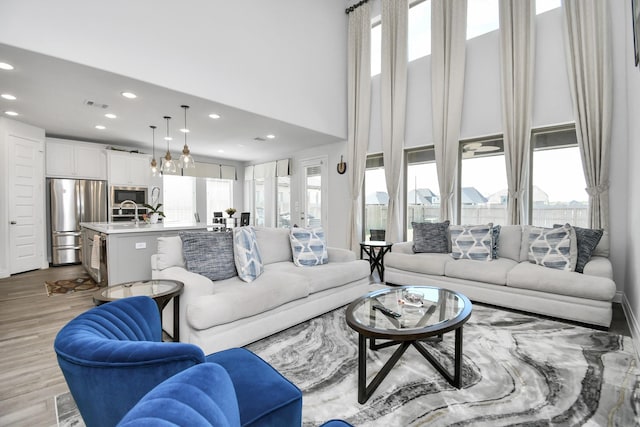 living room featuring sink, a high ceiling, and light wood-type flooring