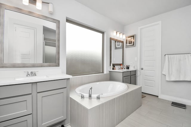 bathroom featuring tile patterned flooring, vanity, and tiled tub