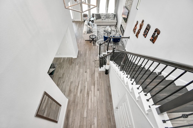 staircase with a towering ceiling, hardwood / wood-style flooring, and a notable chandelier