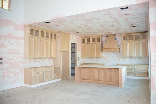 kitchen with a kitchen island, light brown cabinetry, and custom range hood