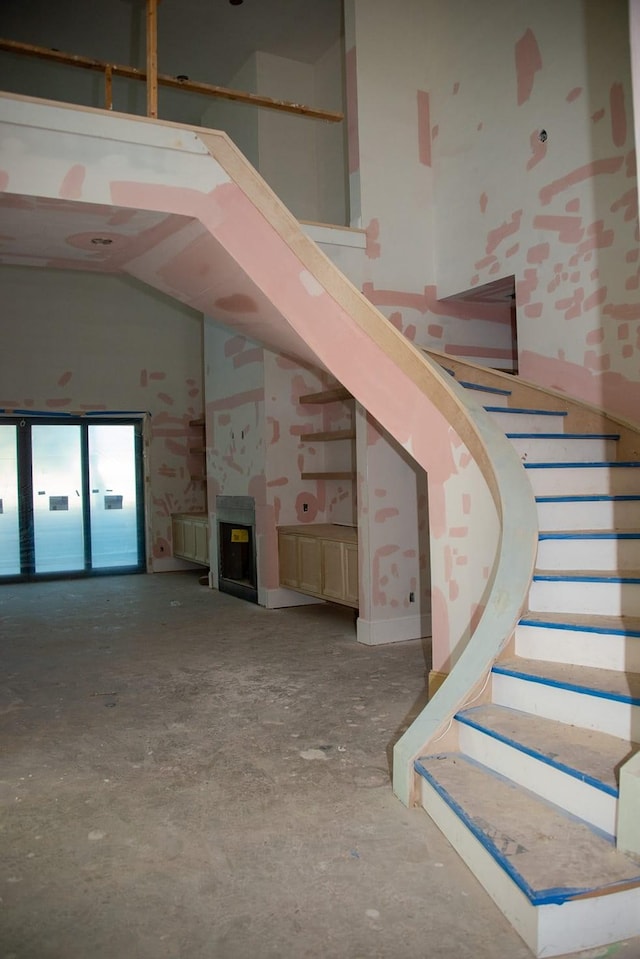 stairway with high vaulted ceiling and concrete flooring