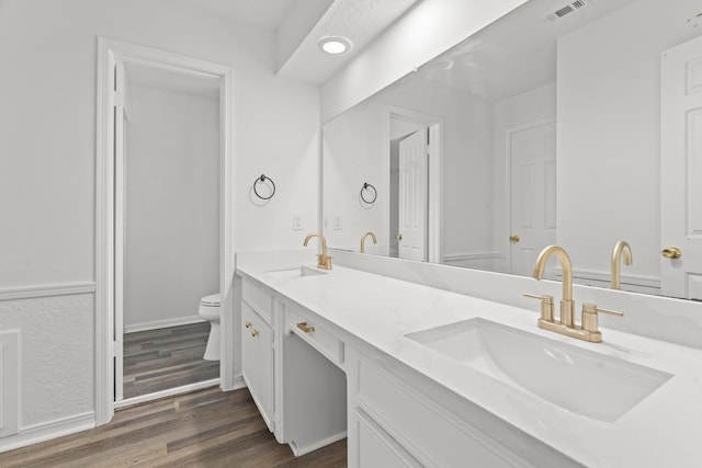 bathroom with visible vents, a sink, toilet, and wood finished floors