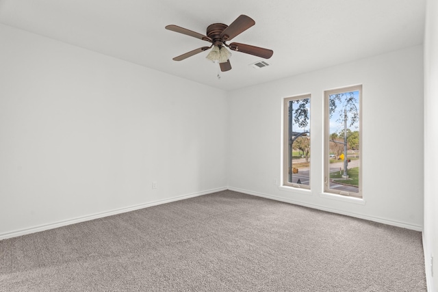 carpeted empty room with baseboards, visible vents, and ceiling fan