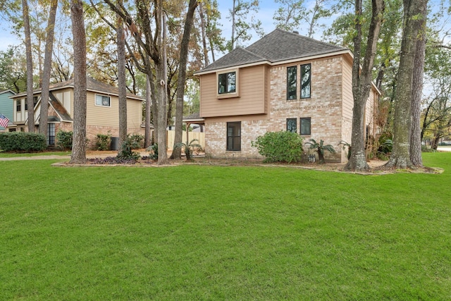 view of front of home with brick siding, a front lawn, and roof with shingles