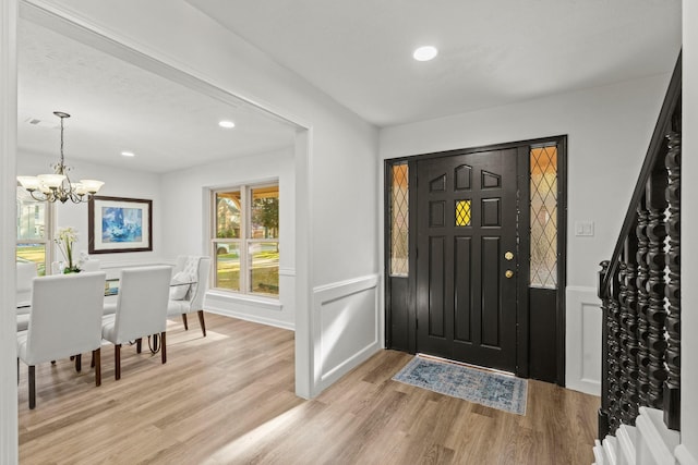 foyer entrance featuring light wood-style floors, recessed lighting, a wainscoted wall, and an inviting chandelier