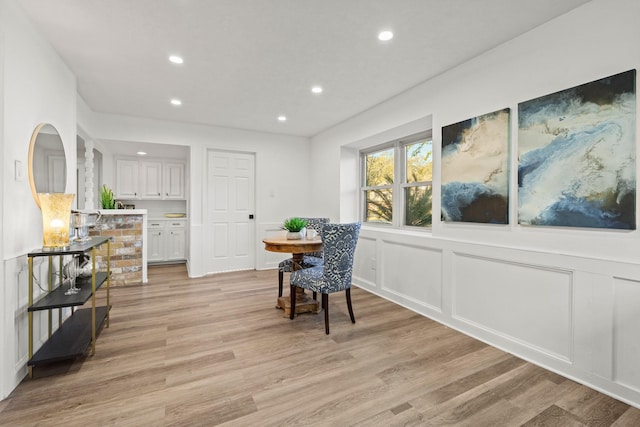 dining room with a wainscoted wall, light wood-style flooring, a decorative wall, and recessed lighting