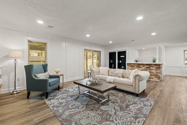 living room with light wood finished floors, a wealth of natural light, and a decorative wall