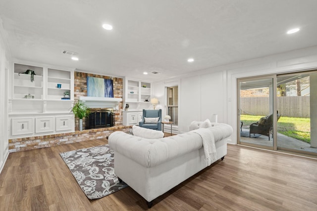 living room with hardwood / wood-style floors, a fireplace, and built in shelves