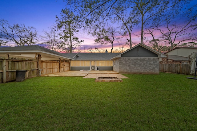 back house at dusk with a yard and a patio area