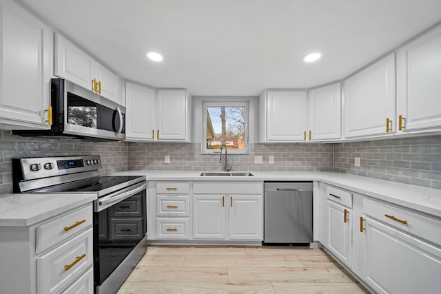 kitchen featuring sink, appliances with stainless steel finishes, white cabinetry, tasteful backsplash, and light stone countertops