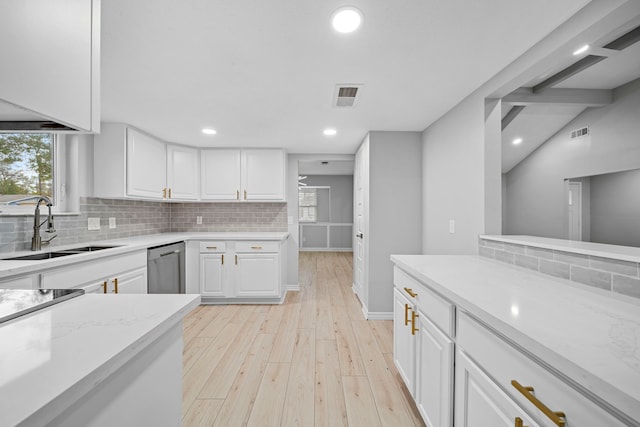 kitchen featuring sink, dishwasher, white cabinetry, backsplash, and light stone countertops