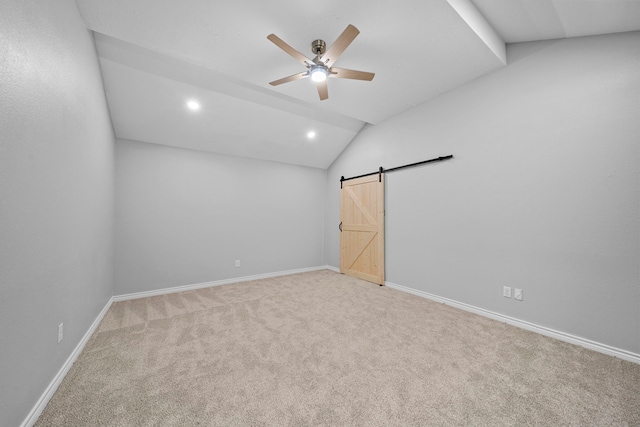 unfurnished room with lofted ceiling, light carpet, a barn door, and ceiling fan