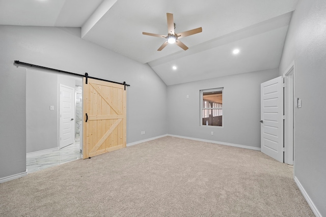 carpeted spare room with ceiling fan, a barn door, and vaulted ceiling