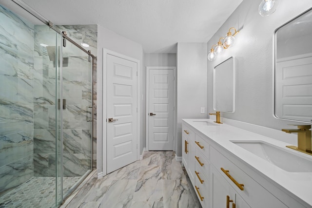 bathroom with vanity, a shower with shower door, and a textured ceiling