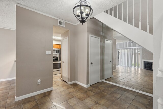 hall with ornamental molding, an inviting chandelier, and a textured ceiling