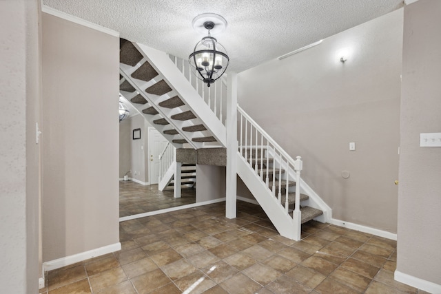 stairs with an inviting chandelier and a textured ceiling