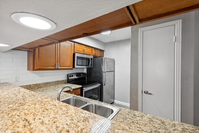 kitchen featuring sink, stainless steel appliances, backsplash, and light stone countertops