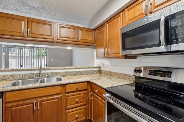 kitchen featuring sink, a textured ceiling, decorative backsplash, tile patterned floors, and appliances with stainless steel finishes