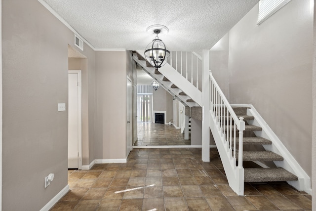 stairs with a textured ceiling, crown molding, and a chandelier