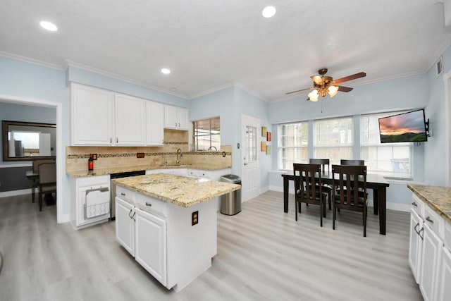 kitchen with backsplash, a center island, ornamental molding, light stone countertops, and white cabinets