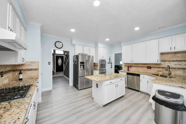 kitchen with sink, a center island, appliances with stainless steel finishes, light stone countertops, and white cabinets