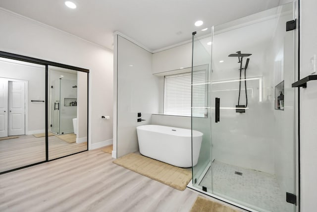 bathroom with crown molding, plus walk in shower, and hardwood / wood-style floors