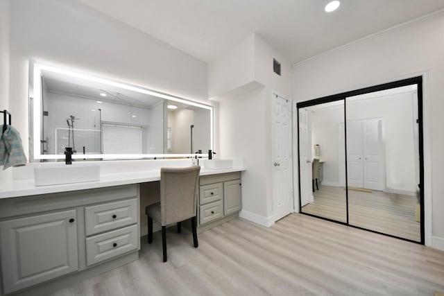 bathroom featuring vanity, hardwood / wood-style floors, ornamental molding, and walk in shower