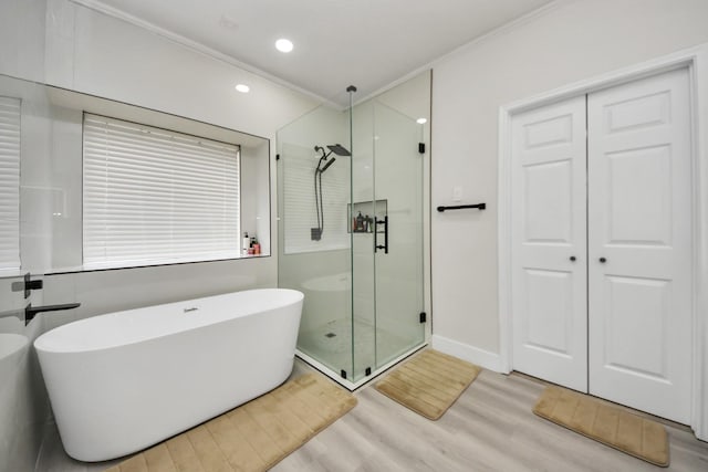 bathroom featuring ornamental molding, wood-type flooring, and shower with separate bathtub