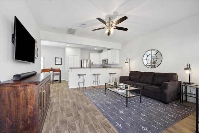 living room featuring ceiling fan and dark hardwood / wood-style floors